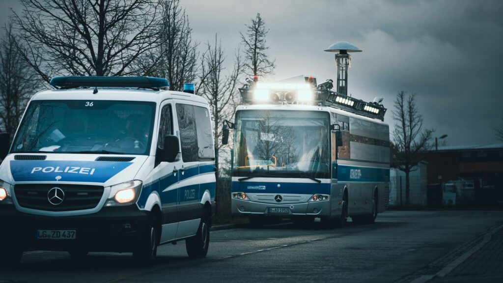 Ein Polizeiwagen und der "Adenauer" fahren hintereinander auf einer Straße.