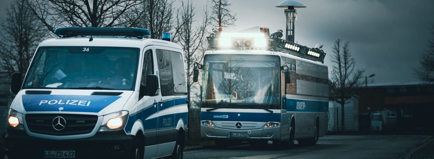 Ein Polizeiwagen und der "Adenauer" fahren hintereinander auf einer Straße.