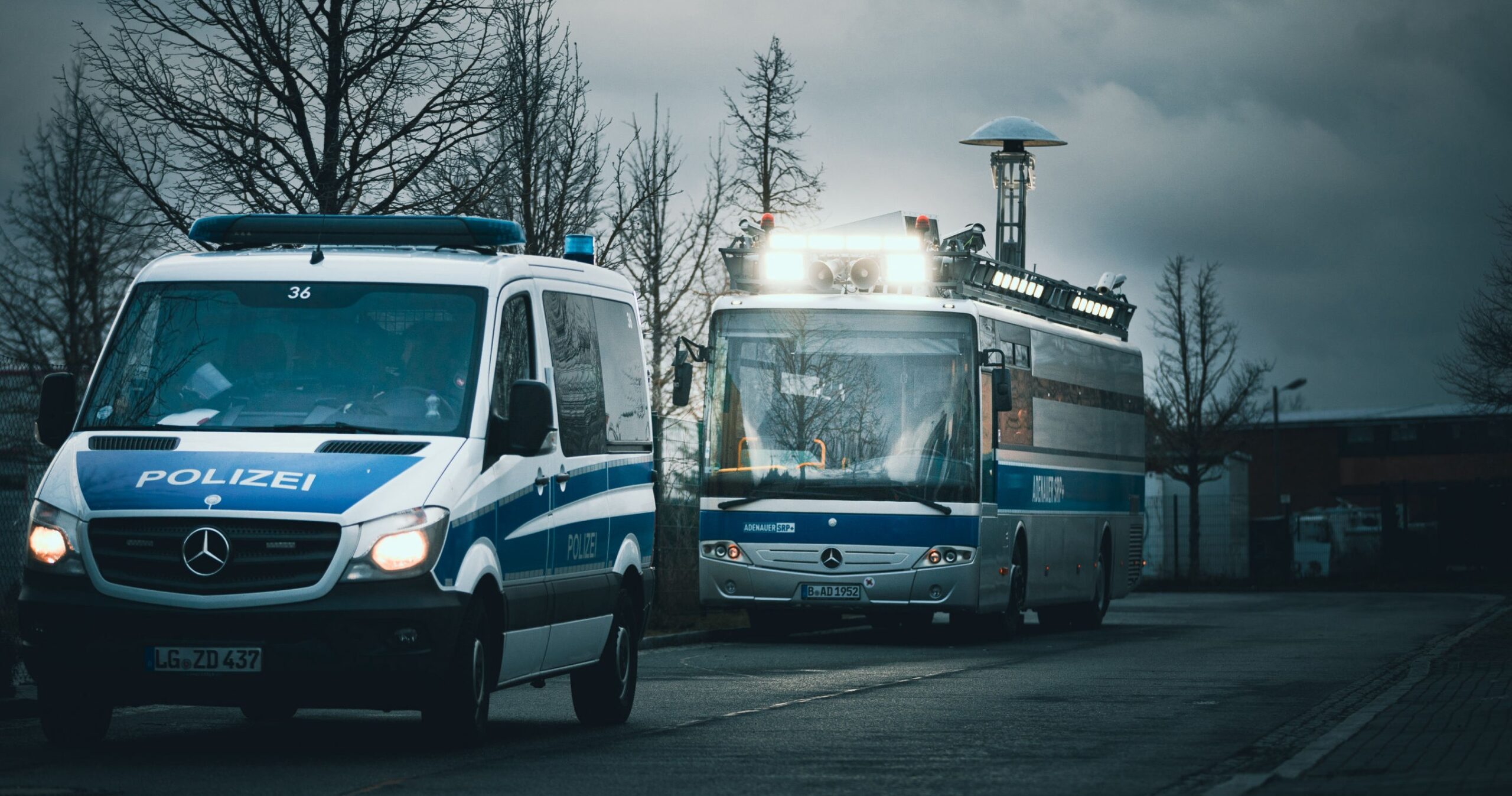 Ein Polizeiwagen und der "Adenauer" fahren hintereinander auf einer Straße.